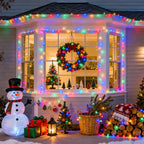 Multicolor 100 LED battery string lights framing a house window with Christmas wreath