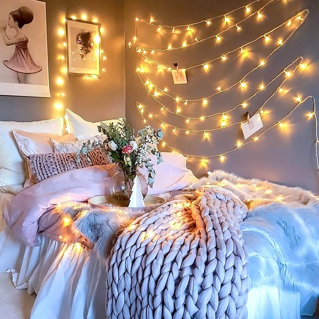 Warm white 100 LED battery string lights draped over a cozy bedroom wall