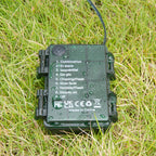 Green IP65 waterproof battery case covered in water drops lying on grass with 9 mode labels