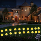 Warm white solar crystal bubble ball garden stake lights glowing at night in front of a stone villa